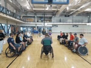 Group of disabled people sitting in their wheelchairs discussing in a indoor sports arena