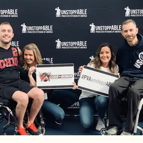 Two disabled men sitting in their wheel chairs with their female friends showing their awards